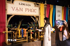 Người dân chụp ảnh lưu lại khoảnh khắc tại gian trưng bày của Làng lụa Vạn Phúc. (Ảnh: Khánh Hòa/TTXVN)