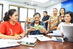 Người dân đến đăng ký nhận quà tại điểm chi trả phường Bồ Đề (Hà Nội). (Ảnh: Minh Quyết/TTXVN)