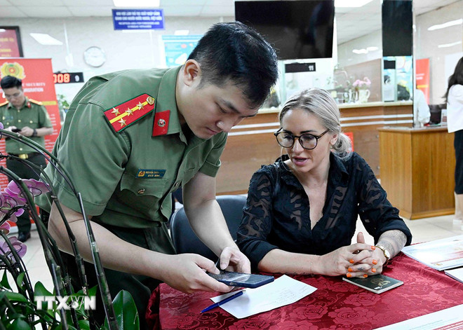 Cán bộ, chiến sỹ Cục quản lý xuất nhập cảnh, Bộ Công an hướng dẫn người nước ngoài làm thủ tục cấp tài khoản định danh điện tử. (Ảnh: Phạm Kiên/TTXVN) ttxvn-dinh-danh-dien-tu-nguoi-nuoc-ngoai-4.jpg