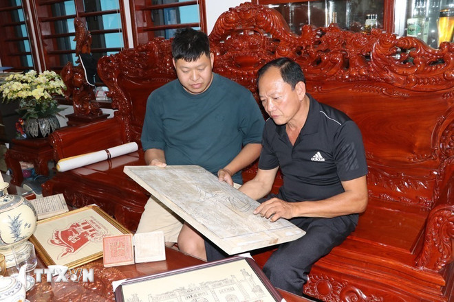Die Kunsthandwerker Nguyen Cong Trang (rechts) und Nguyen Cong Dat diskutieren über Holzschnitt- und Druckarbeiten zum Thema der Reliquienstätte Con Son-Kiep Bac. (Foto: Manh Minh/VNA) ttxvn-hai-phong-bao-ton-nghe-khac-in-moc-ban-5.jpg