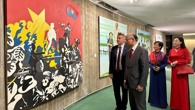 PCF National Secretary Fabien Roussel introduces to Vietnamese Ambassador to France Dinh Toan Thang a propaganda painting painted by French artists in the 1960s. (Photo: Nguyen Thu Ha/VNA) tinh-huu-nghi-va-hoi-uc-ve-ngay-viet-nam-thong-nhat-thap-sang-tru-so-dang-cong-san-phap-8006930-1.jpg