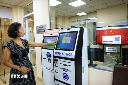 Người dân Hà Nội lấy số thứ tự xếp hàng làm thủ tục hành chính. (Ảnh: Tuấn Anh/TTXVN)