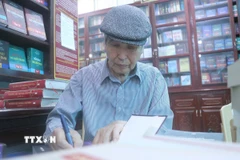 Nhà văn Minh Chuyên ký tặng sách cho độc giả. (Ảnh: Vũ Quang/TTXVN)