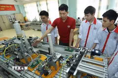 Thầy giáo giới thiệu mô hình tự động hoá cho sinh viên lớp điện tử công nghiệp tại một trường cao đẳng nghề công nghệ cao. (Ảnh: Hoàng Hiếu/TTXVN)