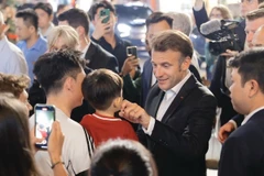 Tổng thống Pháp và Phu nhân gặp gỡ người dân trên đường tản bộ khu vực phố cổ Hà Nội, tối 26/5/2025. (Ảnh: TTXVN)