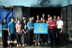 Phó Chủ tịch Liên đoàn Lao động tỉnh Bắc Giang Lê Đức Thọ trao kinh phí hỗ trợ cho doanh nghiệp, người lao động Công ty Cổ phần May Năm Châu. (Ảnh: Đồng Thúy/TTXVN)