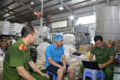 Lực lượng Công an làm việc với Công ty Trách nhiệm hữu hạn sản xuất và xuất nhập khẩu Nhật Minh Food. (Ảnh: TTXVN phát)