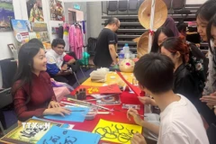 Cô giáo Nguyễn Thụy Thiên Hương (trái) với các sinh viên của trường Đại học Malaya trong một tiết học tìm hiểu và học viết Thư pháp Việt. (Ảnh: Hằng Linh/TTXVN)