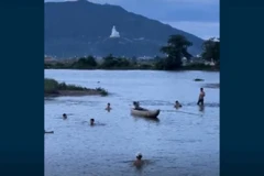 (Ảnh cắt từ clip) Người dân nỗ lực tìm kiếm tại điểm ba học sinh bị đuối nước. (Ảnh: TTXVN phát)