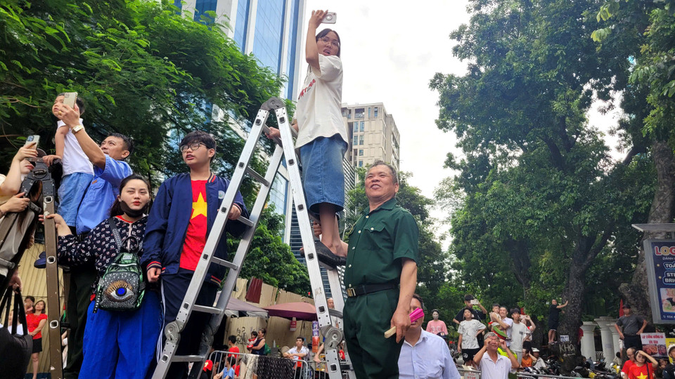 Một số người có thang đã ưu tiên trẻ nhỏ và người cao tuổi, đặc biệt là cựu chiến binh đứng cùng hoặc cho mượn thang. (Ảnh: Minh Anh/Vietnam+)