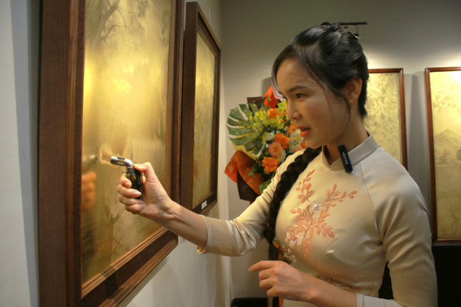 Besøkende tester ilden i malerier med bruk av brennere. (Foto: Minh Anh/Vietnam+) img-7046.jpg