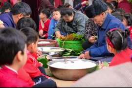 Học sinh Trường Tiểu học Dương Liễu B (Hà Nội) gói trải nghiệm gói bánh chưng ngày Tết dưới sự hướng dẫn của người lớn. (Ảnh: NTCC)