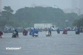 Người dân Hà Nội di chuyển khó khăn qua các tuyến phố. (Ảnh: Hoài Nam/Vietnam+)