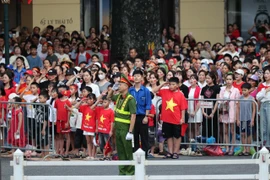 Người dân chào cờ trước giờ tổng duyệt. (Ảnh: Minh Sơn/Vietnam+)