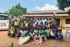 Ông Salim - Giám đốc Trung tâm (đứng ở giữa) cùng các em nhỏ chụp ảnh kỉ niệm cùng Tổ công tác. (Ảnh: PV/Vietnam+)