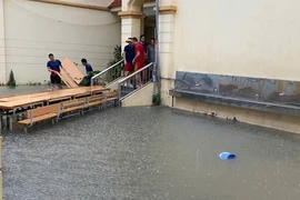 Trường Tiểu học Nam Trung Yên, nước ngập toàn bộ sân trường. Thầy cô giáo đã kê bàn ghế ra sân trường để làm cầu cho phụ huynh đón học sinh. (Ảnh: PHCC)