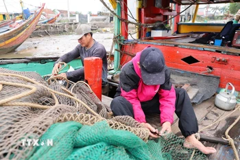 Ngư dân sửa sang, vá lưới chuẩn bị cho chuyến đi biển. (Ảnh: Xuân Tiến/TTXVN)