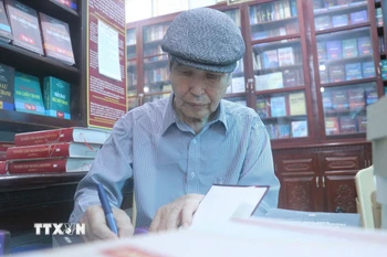 Nhà văn Minh Chuyên ký tặng sách cho độc giả. (Ảnh: Vũ Quang/TTXVN)