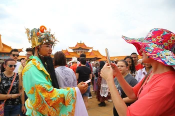 Du khách thích thú chụp ảnh lưu niệm cùng nhân vật Thần Tài trong dân gian của người châu Á. (Ảnh: Hồng Minh/TTXVN)