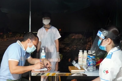 Lực lượng y tế tại chốt kiểm dịch chân cầu Yên Dũng nối tỉnh Bắc Ninh và Bắc Giang hỗ trợ người dân khai báo y tế. (Ảnh: Đinh Văn Nhiều/TTXVN)