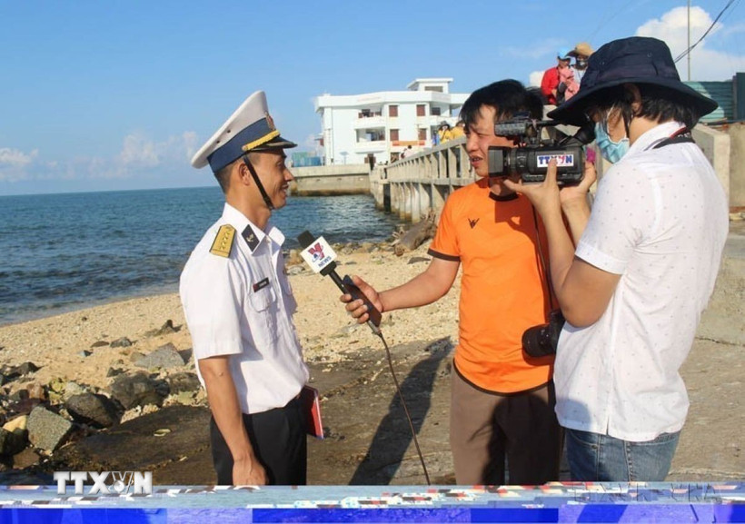 Các phóng viên Thắng Trung (cầm mic) và Sỹ Tuyên (TTXVN) quay phỏng vấn cán bộ hải quân trực tiếp làm nhiệm vụ canh gác bảo vệ trên đảo Đá Thị, Trường Sa hồi tháng 4/2021. (Ảnh: Phan Sáu/TTXVN)