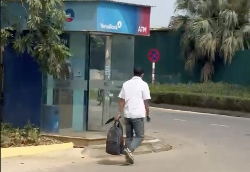 Người dân quay lại cảnh nghi phạm xách túi đựng tiền đi bộ ra ngoài.