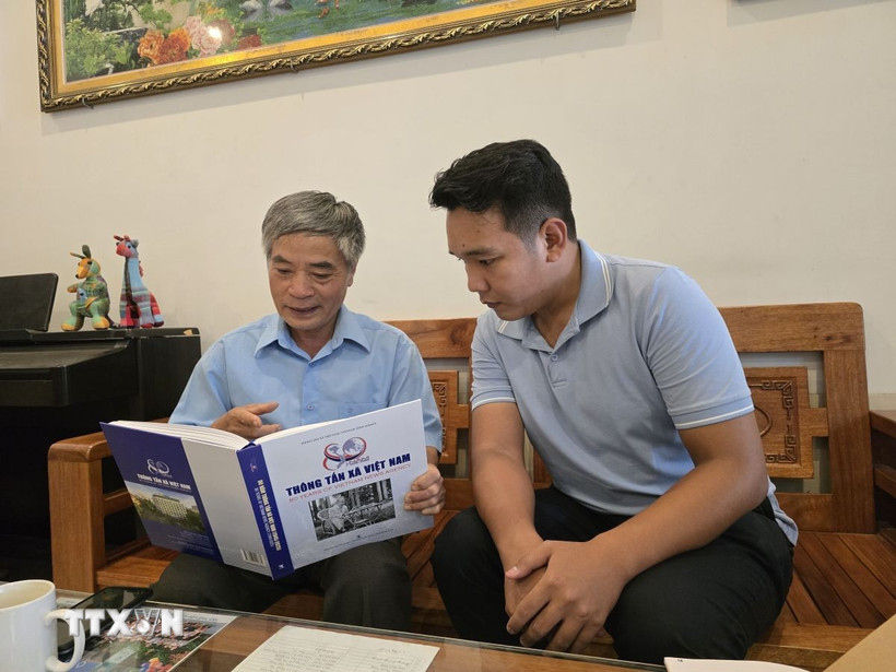 Ông Trịnh Quang Dân (bên trái, nguyên là điện báo viên của TTXVN) chia sẻ với phóng viên trẻ về những kỷ niệm đáng nhớ trong suốt quá trình công tác. (Ảnh: TTXVN phát)
