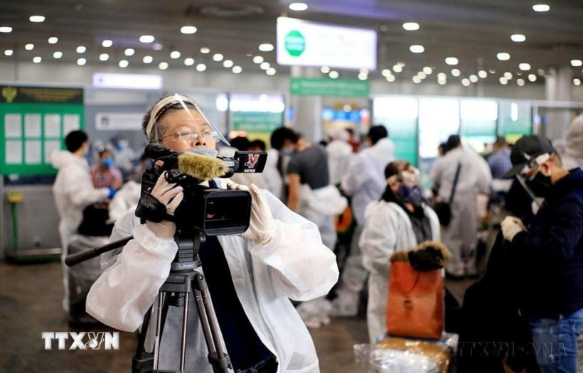 Trưởng Cơ quan Thường trú TTXVN tại Liên bang Nga, Bùi Duy Trinh đưa tin về chuyến bay đầu tiên đưa hơn 300 công dân Việt Nam từ Liên bang Nga về nước trong bối cảnh đại dịch COVID-19, tại sân bay Sheremetyevo (5/2020). (Ảnh: TTXVN) 