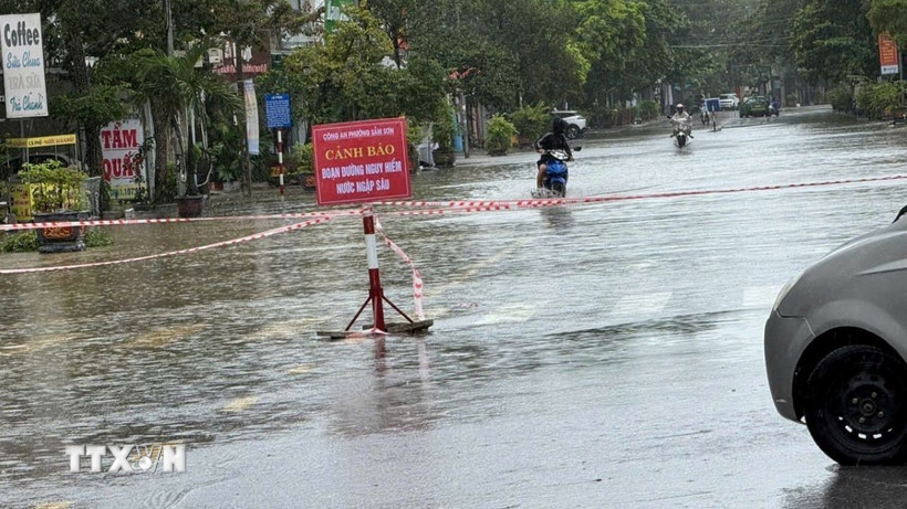 Mưa lớn kèm sóng biển dội nước vào bờ khiến nhiều tuyến đường tại phường Sầm Sơn ngập sâu, cơ quan chức năng phải cắm biển cảnh báo nguy hiểm. (Ảnh: Việt Hoàng/TTXVN)