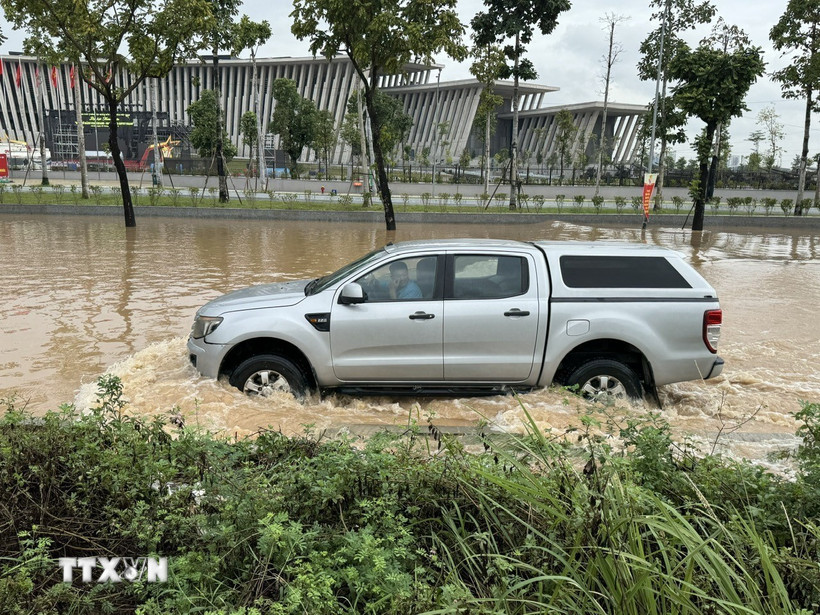 Nước ngập sâu khiến các phương tiện lưu thông khó khăn. (Ảnh: Quốc Lũy/TTXVN)