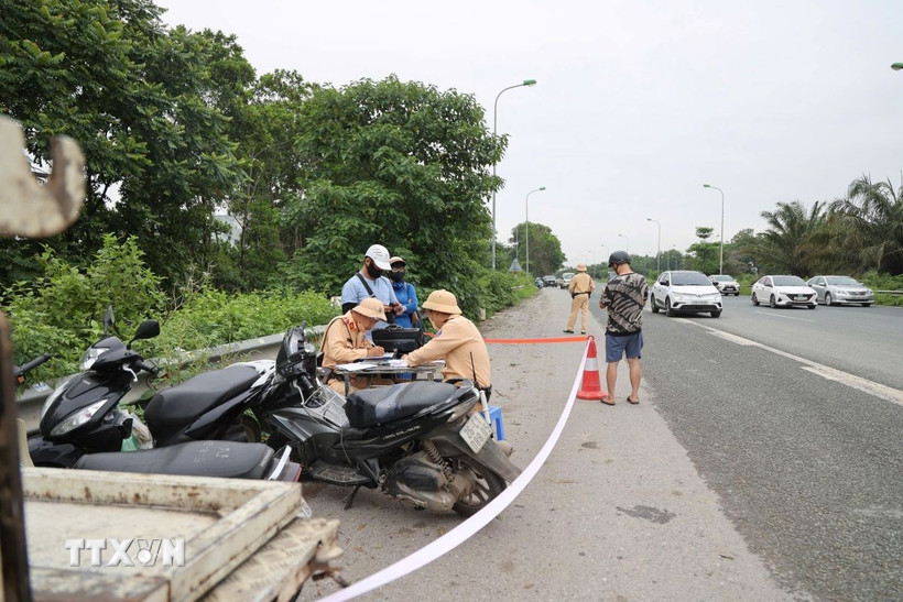 Cảnh sát giao thông xử phạt nhiều người đi xe máy cố tình đi vào cao tốc Đại lộ Thăng Long. (Ảnh: TTXVN phát)