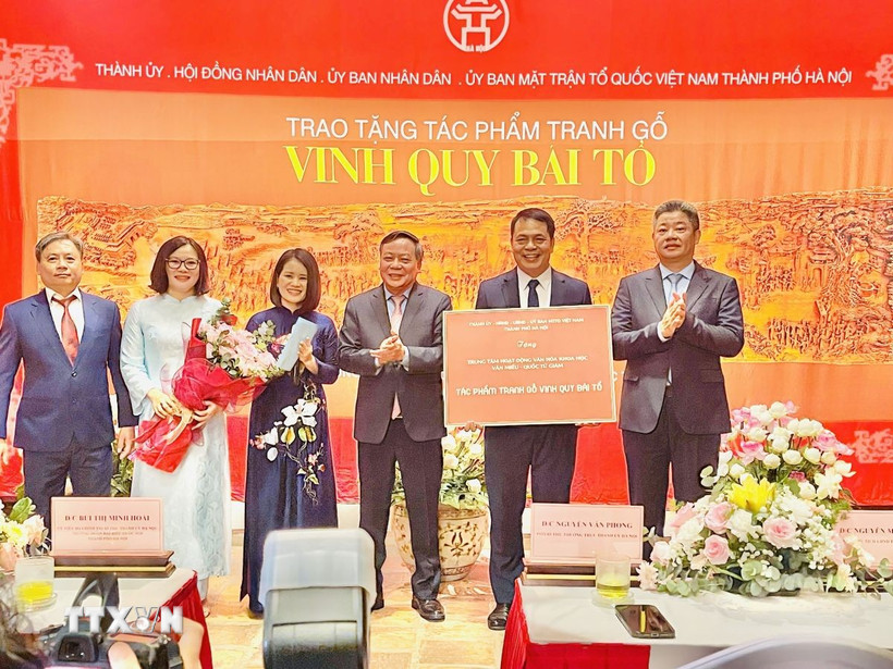 Lãnh đạo thành phố Hà Nội trao chứng nhận tặng tác phẩm tranh gỗ "Vinh Quy Bái Tổ" cho Trung tâm Hoạt động Văn hóa Khoa học Văn Miếu - Quốc Tử Giám. (Ảnh: Tuyết Mai/TTXVN)