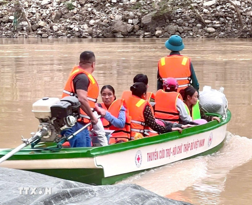 Giáo viên, học sinh được lực lượng chức năng đưa qua sông bằng thuyền. (Ảnh: TTXVN phát)
