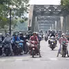 Người dân thành phố Huế mặc đồ bảo hộ chống nắng khi, di chuyển ở phía Bắc cầu Trường Tiền, phường Phú Xuân. (Ảnh: Nguyên Lý/TTXVN)