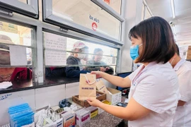Nhân viên y tế cấp phát thuốc bảo hiểm y tế cho người bệnh. (Ảnh: T.G/Vietnam+)