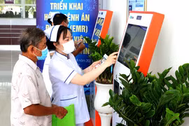 Nhân viên y tế hướng dẫn người dân đăng ký khám bệnh qua hệ thống kios tự động tại Bệnh viện Đa khoa Trà Vinh, tỉnh Vĩnh Long. (Ảnh: TTXVN)