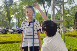 Nhân viên y tế đo chiều cao cho trẻ tại ngày hội. (Ảnh: PV/Vietnam+)