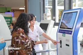 Người bệnh làm thủ tục ở ki-ốt đăng ký khám tự động tại Bệnh viện Đa khoa Đức Giang. (Ảnh: PV/Vietnam+)