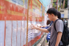 Người dân nghiên cứu danh sách các ứng cử viên được niêm yết tại các điểm bầu cử. (Ảnh: Khoa Chương/TTXVN)