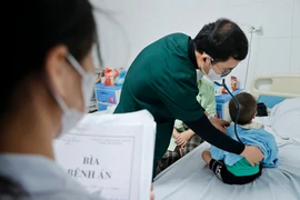 Bác sỹ khám cho bệnh nhi đang điều trị tại bệnh viện Thanh Nhàn. (Ảnh: Minh Quyết/TTXVN)