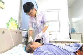 Bác sỹ thăm khám và điều trị cho bệnh nhân. (Ảnh: PV/Vietnam+)