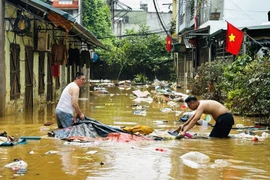 Người dân dọn dẹp nhà cửa sau trận lụt. (Ảnh: Đức Thọ/TTXVN)