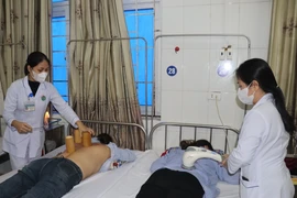 Chưa bệnh cho người dân bằng y học cổ truyền. (Ảnh: TTXVN/Vietnam+)
