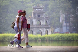 Du khách nước ngoài đi dạo bên hồ Hoàn Kiếm. (Ảnh: Tuấn Đức/TTXVN)