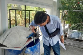 Kiểm tra các thùng phuy chứa nước trong gia đình, môi trường muỗi sinh sản loăng quăng. (Ảnh: TTXVN)