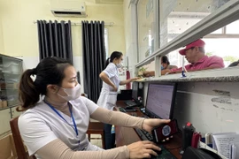 Nhân viên y tế quét mã lấy số và đăng ký khám bệnh tại các ki-ốt phát số tự động. (Ảnh: Đinh Hương/TTXVN)
