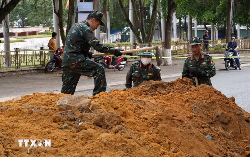 Lực lượng chức năng tiến hành đào rãnh thăm dò dọc đường Trường Chinh (Quảng Ngãi). (Ảnh: Dư Toán/TTXVN)