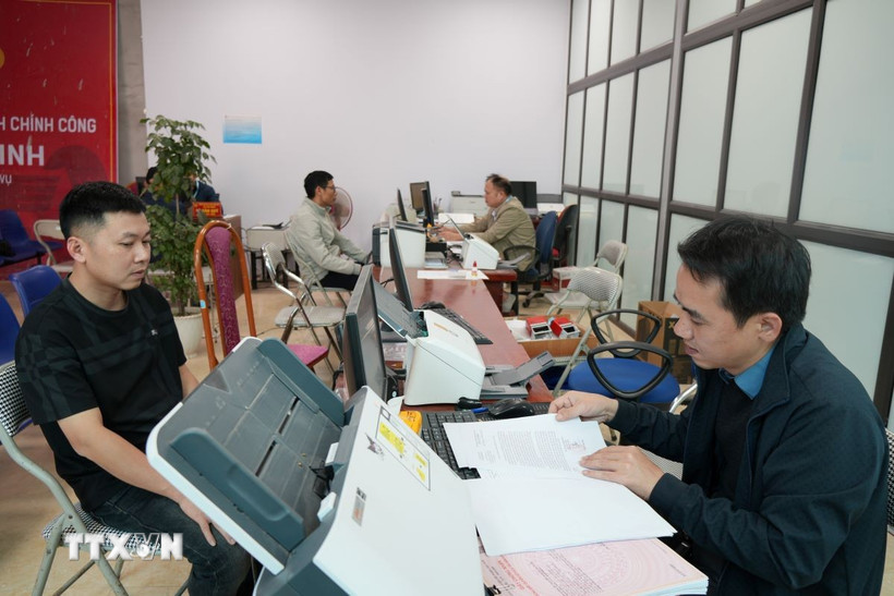 Cán bộ xã Tân Minh giải quyết thủ tục cho người dân. (Ảnh Tiến Vĩnh/TTXVN)