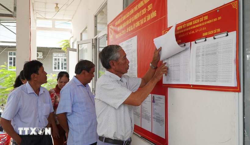 Người dân xem danh sách cử tri được niêm yết tại điểm bỏ phiếu. (Ảnh: Nhựt An/TTXVN)