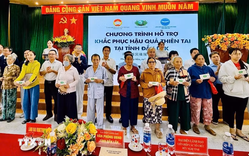 Trao tiền, quà hỗ trợ người dân vùng lũ. (Ảnh: CTV/TTXVN)
